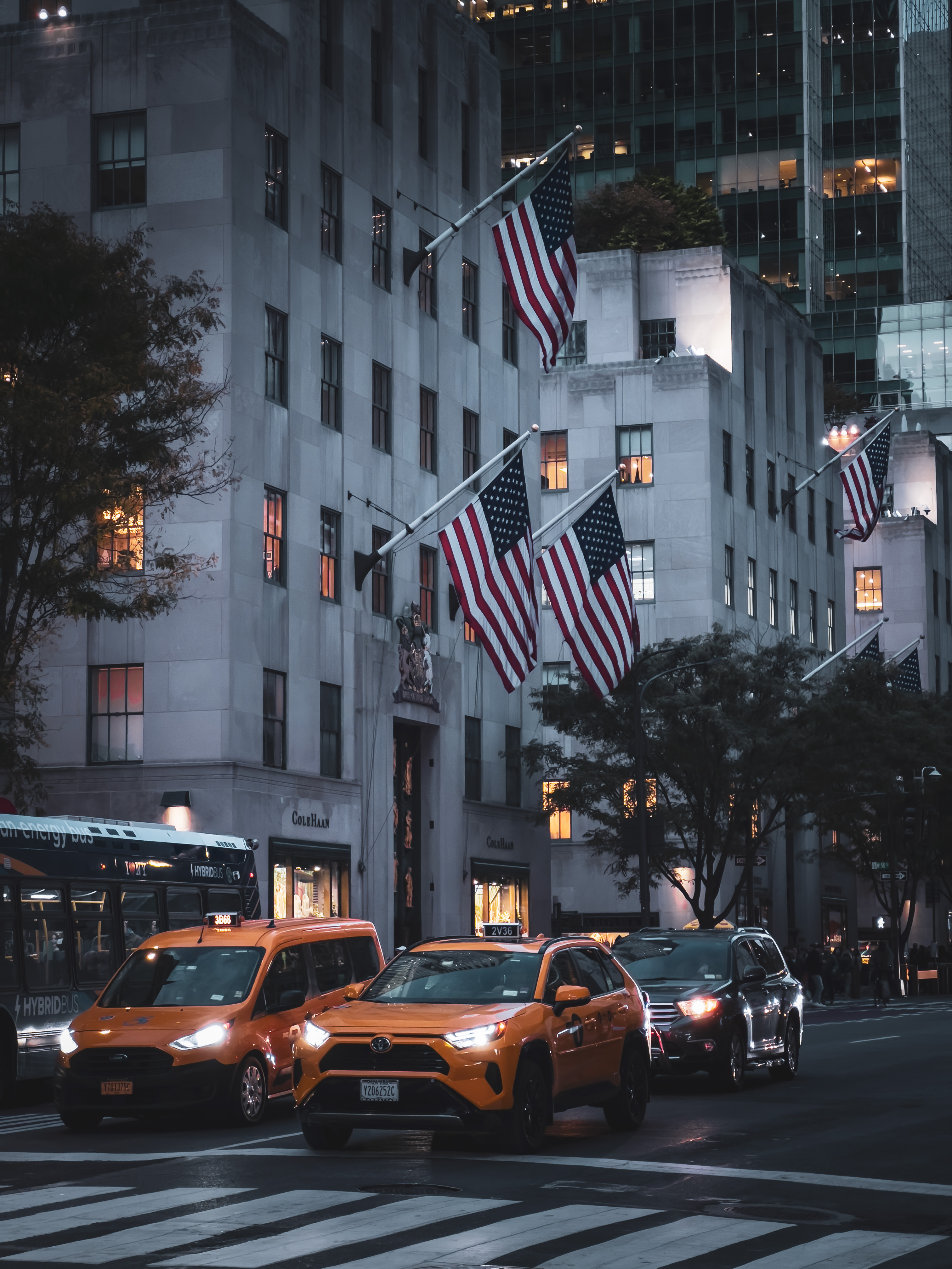 American flags above yellow taxis on a New York City street at night